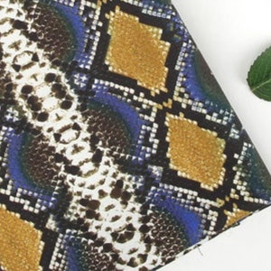 May include: A fabric with a snake skin pattern in shades of brown, blue, and yellow. The pattern is a repeating diamond shape.