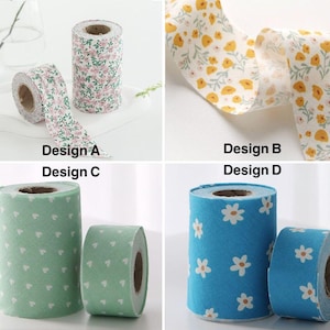 May include: A selection of decorative fabric rolls featuring floral and patterned designs. Designs include pink and white flowers, yellow flowers, green hearts, and white daisies on blue. The text "Design A", "Design B", "Design C", and "Design D" is visible.