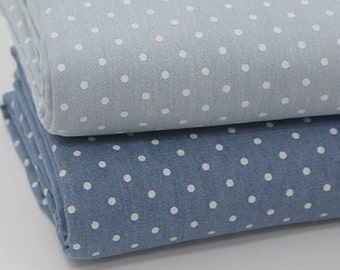 May include: Two pieces of blue denim fabric with white polka dots. The top piece is a lighter shade of blue than the bottom piece.