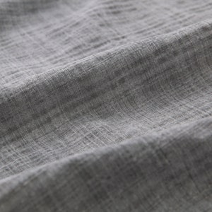 May include: Close-up of a gray textured fabric with a subtle woven pattern.