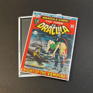 May include: A vintage comic book cover featuring Dracula, a vampire, carrying a woman in a green dress. The cover is titled "Dracula Lives! The Tomb of Dracula" and "Night of the Vampire!" with a red and white background.
