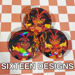 May include: Three round buttons with a cartoon character design in shades of red, orange, and yellow. The character has a wide, toothy grin and spiky hair. The buttons have a holographic effect. The text "SIXTEEN DESIGNS" is at the bottom.