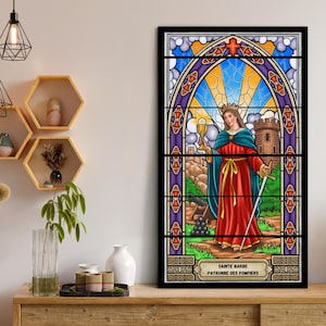 Op de afbeelding: Een gebrandschilderd raam met daarop een afbeelding van Sint Barbara, de beschermheilige van brandweerlieden. De afbeelding toont haar met een kelk en een zwaard in de hand, staande voor een kasteel met een kanon en kanonballen. De tekst onderaan luidt "Sainte Barbe Patronne des Pompiers".