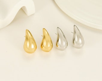 May include: A set of four teardrop-shaped earrings. Two earrings are gold and two are silver.