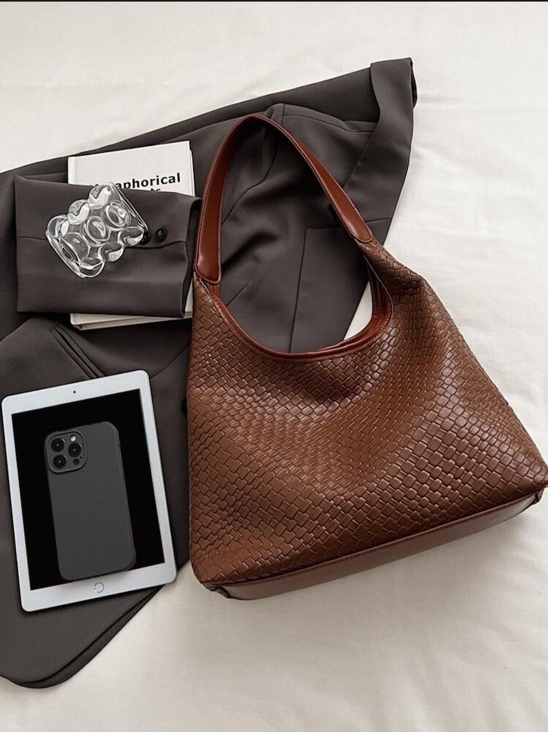 May include: A brown woven leather handbag with a single strap. The bag has a rectangular shape with a curved top.