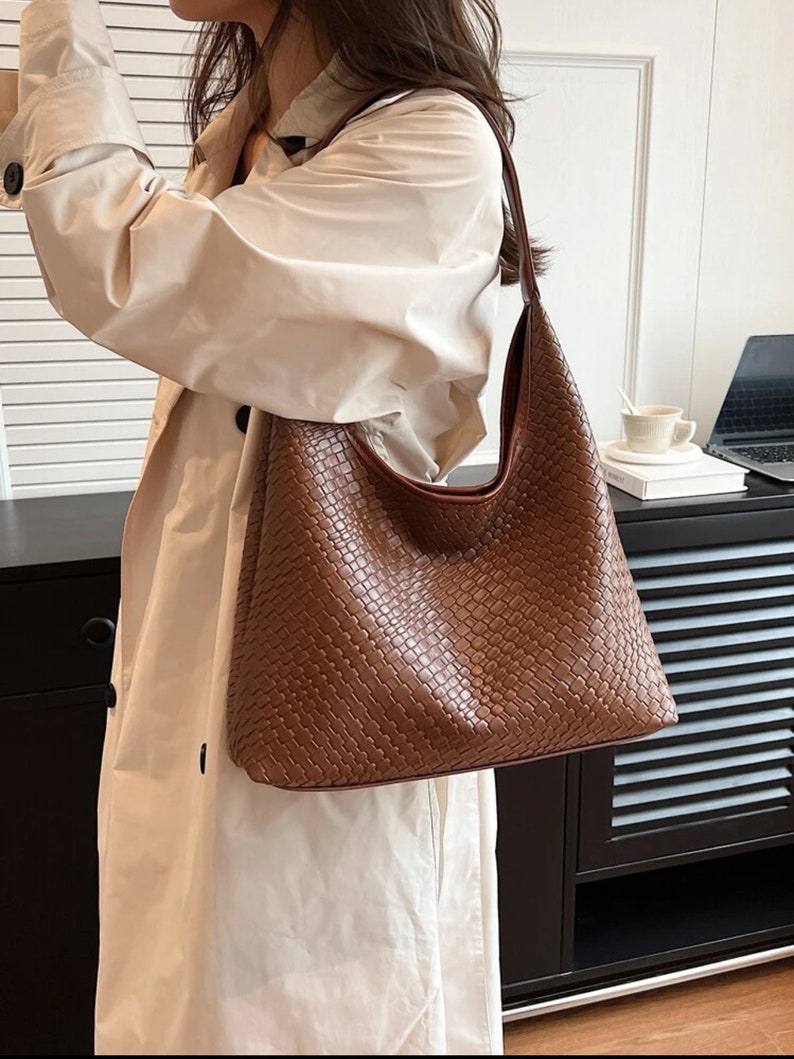 May include: A brown woven leather shoulder bag with a long strap. The bag has a slouchy, casual style.