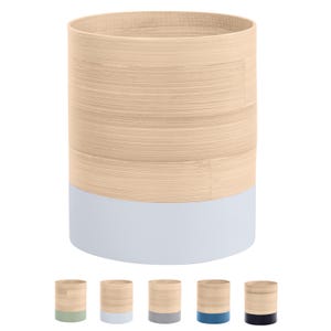 May include: A cylindrical bamboo trash can with a light blue bottom. The can is made of natural bamboo and has a smooth, polished finish.