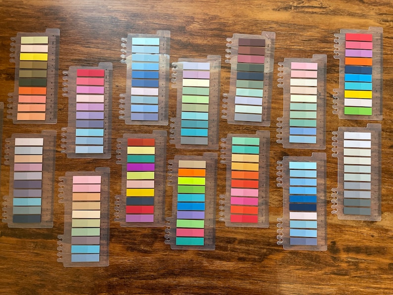May include: A set of 15 color swatches, each with 10 different shades of color. The swatches are arranged in rows on a wooden surface. The colors include shades of blue, green, yellow, orange, red, purple, pink, and brown.