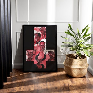 Könnte beinhalten: Ein schwarzer gerahmter Druck eines roten und schwarzen umgekehrten Pentagramms mit fünf Figuren in der Mitte. Die Figuren sind alle Männer mit dunklen Haaren und tragen dunkle Kleidung. Der Druck ist vor einer weißen Wand mit einer Topfpflanze im Vordergrund platziert.