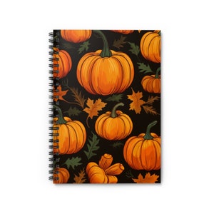 May include: A spiral bound notebook with a black background and a repeating pattern of orange pumpkins and brown leaves.