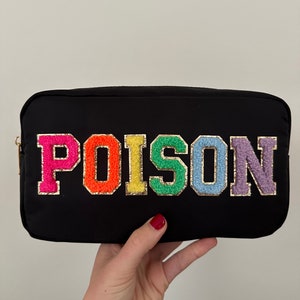 Peut inclure: Une trousse de maquillage noire avec un motif arc-en-ciel "POISON".