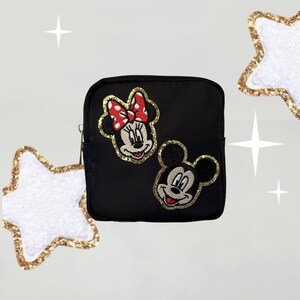 May include: Black zippered pouch with embroidered images of Mickey Mouse and Minnie Mouse. Mickey Mouse is wearing a red and white bow tie and Minnie Mouse is wearing a red and white bow.