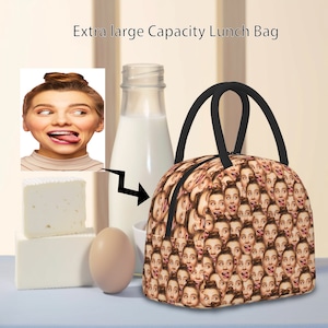 May include: A brown lunch bag with a repeating pattern of a woman's face. The bag has a black handle and a zipper closure.