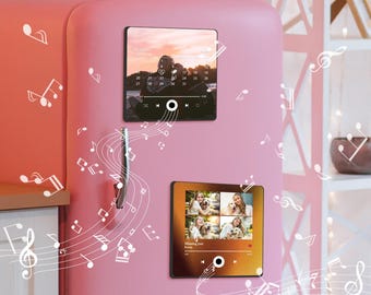 Könnte beinhalten: Zwei quadratische Bilderrahmen mit magnetischer Rückseite sind an einem rosafarbenen Kühlschrank befestigt. Die Rahmen spielen Musik und haben einen Play-, Pause- und Rückspulknopf. Der obere Rahmen zeigt ein Foto eines Paares, das am Strand bei Sonnenuntergang steht. Der untere Rahmen zeigt eine Collage von Fotos einer Familie mit einem Hund. Der Text auf dem unteren Rahmen lautet "Missing you already".