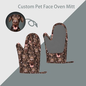 May include: A pair of brown oven mitts with a pattern of a dog's face. The mitts are made of a heat-resistant material and have a textured surface. The dog's face is brown and has a black nose and eyes. The dog is smiling with its mouth open.