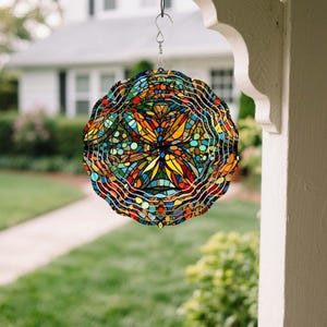 May include: A colorful, stained-glass style wind spinner with a circular design. The spinner features a vibrant array of colors including red, orange, yellow, blue, and green. It hangs from a metal hook, adding a decorative touch to outdoor spaces.
