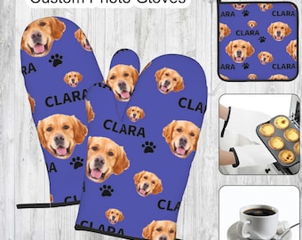 May include: A pair of blue oven mitts with a pattern of golden retriever dogs and the name "Clara" printed on them. The mitts are shown with a matching blue pot holder.