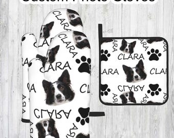 May include: Set of two white oven mitts and a white pot holder with a black border. The mitts and pot holder feature a repeating pattern of a black and white dog with the name "Clara" written in black.