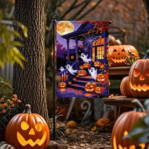 May include: A Halloween garden flag featuring a spooky house with ghosts, jack-o'-lanterns, and a full moon. The flag is displayed outdoors with carved pumpkins in the foreground, creating a festive autumn scene.