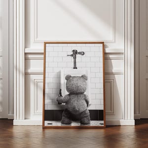 Humorous bathroom poster showing a plush bear with a beer in a playful black and white scene.