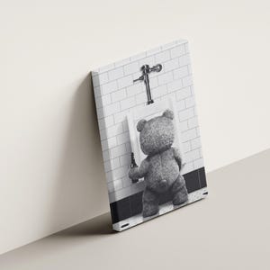 Quirky bathroom wall art with a teddy bear at a urinal, combining humor and minimalist photography.