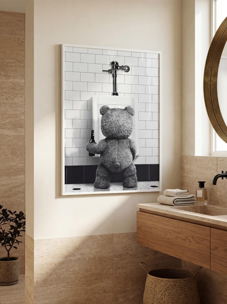 Funny black and white wall art featuring a teddy bear holding a beer while standing at a bathroom urinal.