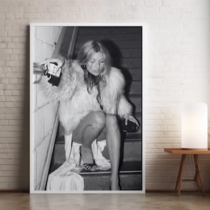 Vintage Kate Moss canvas poster featuring her iconic smoking on stairs pose. A perfect addition to any 90s fashion lover's decor, black and white photography style for a retro, chic vibe. Ideal for celebrity wall art enthusiasts and retro home decor.