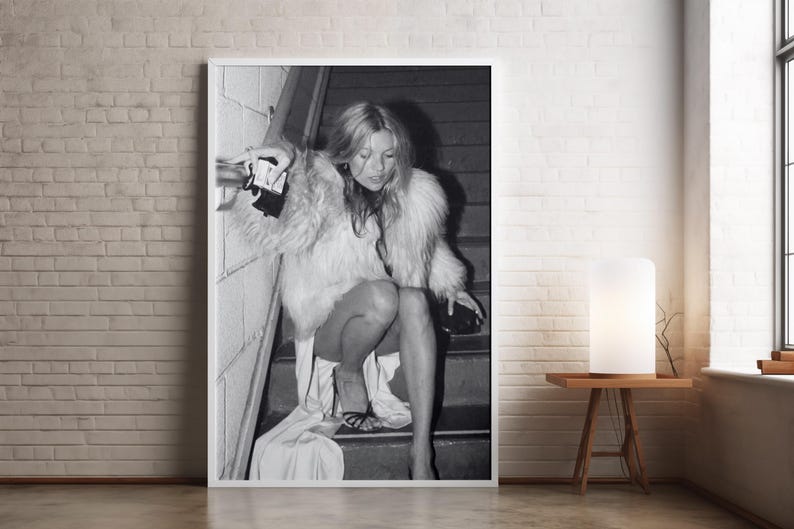 Vintage Kate Moss canvas poster featuring her iconic smoking on stairs pose. A perfect addition to any 90s fashion lover's decor, black and white photography style for a retro, chic vibe. Ideal for celebrity wall art enthusiasts and retro home decor.