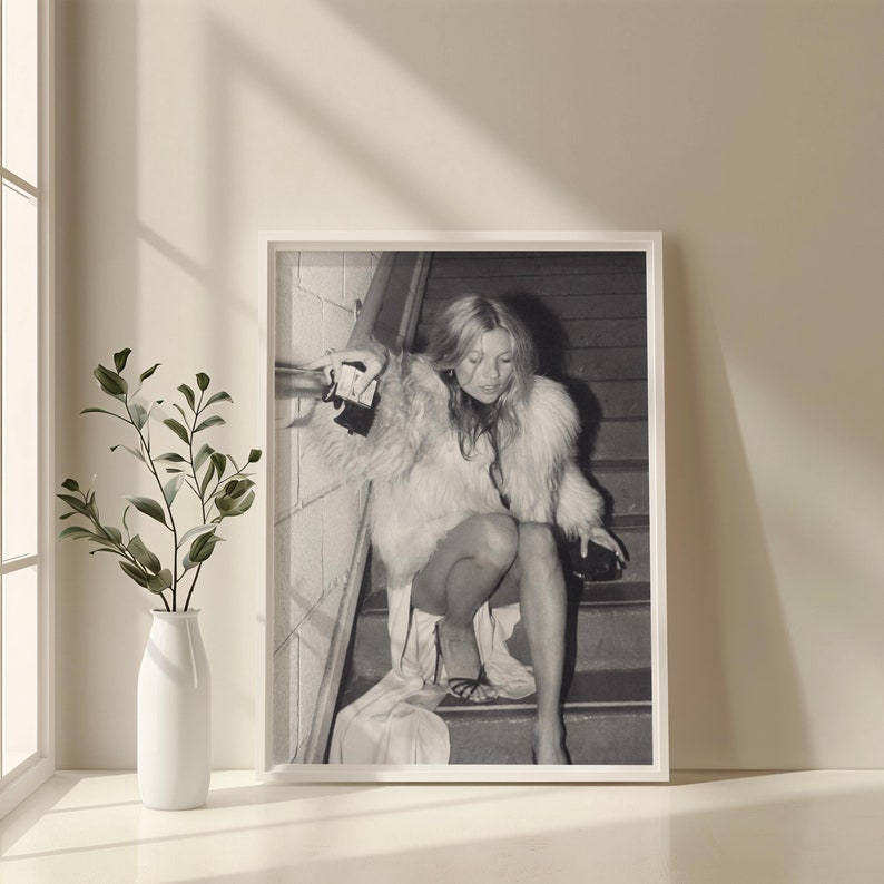 Vintage Kate Moss canvas poster featuring her iconic smoking on stairs pose. A perfect addition to any 90s fashion lover's decor, black and white photography style for a retro, chic vibe. Ideal for celebrity wall art enthusiasts and retro home decor.