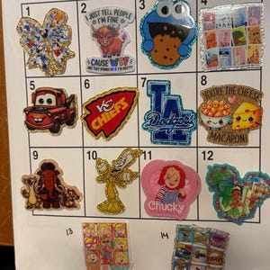 May include: A collection of fourteen assorted decorative stickers arranged in a numbered grid. The stickers feature various pop culture characters, sports logos, and humorous text designs, including a glittery bow, a highland cow, a cookie monster, and cartoon figures, all displayed on a white sheet.