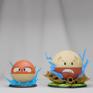 May include: Two cartoon figures, one orange and tan, the other tan and red, with angry expressions. Both have blue lightning effects around them. The figures are on black bases, possibly collectible items.