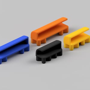 May include: Four small, minimalist benches in blue, orange, black, and yellow. Each bench has a rectangular seat and four short legs. The benches are arranged on a light gray surface.