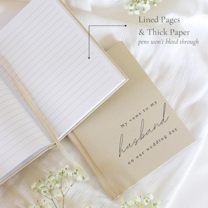 Peut inclure: Un livre de v&oelig;ux de mariage beige avec le texte "My vows to my husband on our wedding day" en &eacute;criture noire. Le livre ouvert r&eacute;v&egrave;le des pages lign&eacute;es avec un signet en ruban. Le texte "Lined Pages & Thick Paper pens won't bleed through" est &eacute;galement visible.