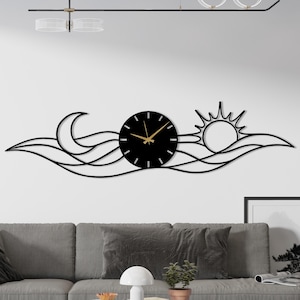 May include: A black metal wall clock featuring a sun, moon, and wave design. The clock has a round face with gold-colored hands and hour markers. The decorative piece is mounted above a gray sofa in a living room setting.