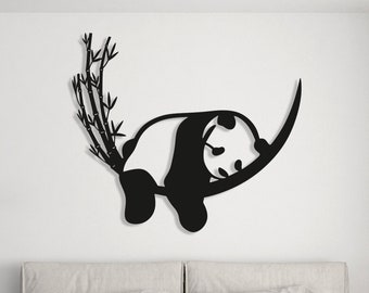 Op de afbeelding: Zwarte metalen wanddecoratie met een pandabeer die aan een tak van bamboe hangt.