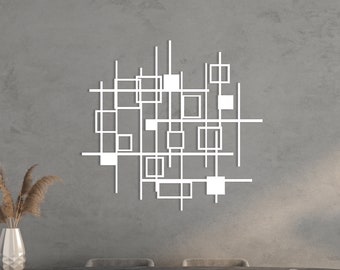 Puede incluir: Una escultura de pared de metal blanco con un diseño geométrico de cuadrados y líneas. La escultura está colgada en una pared gris sobre una mesa de comedor negra con cuatro sillas.