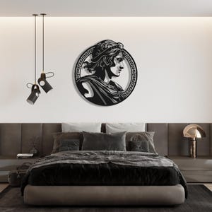 May include: Black metal wall art featuring a profile of a person wearing a crown and a Greek key border.