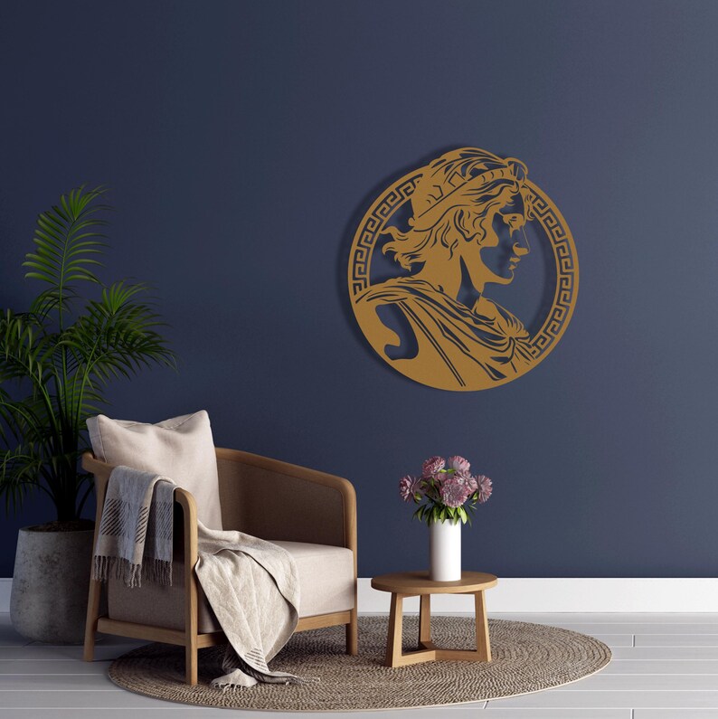 May include: A gold-coloured wall decor featuring a profile of a person with a crown, surrounded by a Greek key pattern.