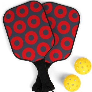 May include: Two black and red patterned pickleball paddles with yellow pickleball balls.