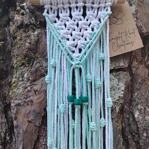 small white and mint macrame wall hanging on driftwood with blue-green/ teal wooden beads
