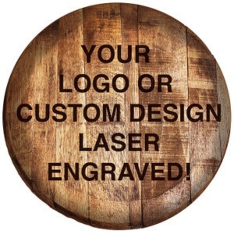 Pode incluir: Uma tampa de barril circular de madeira com uma textura de gr&atilde;o de madeira castanha natural. A superf&iacute;cie &eacute; gravada a laser com o texto: YOUR LOGO OR CUSTOM DESIGN LASER ENGRAVED! O design est&aacute; centrado nas t&aacute;buas verticais da tampa.