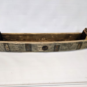 K&ouml;nnte beinhalten: Ein Holzregal aus einem wiederverwendeten Weinfass. Das Regal ist braun und hat eine nat&uuml;rliche Holzoptik. Es hat eine gebogene Form und ist perfekt f&uuml;r die Pr&auml;sentation kleiner Gegenst&auml;nde.