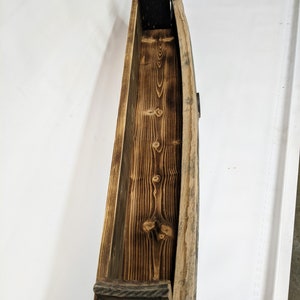 K&ouml;nnte beinhalten: Ein Holzregal aus wiederverwendeten Weinfassdauben. Das Regal ist gebogen und hat eine nat&uuml;rliche Holzoptik. Es ist perfekt f&uuml;r die Pr&auml;sentation von kleinen Gegenst&auml;nden oder Pflanzen.