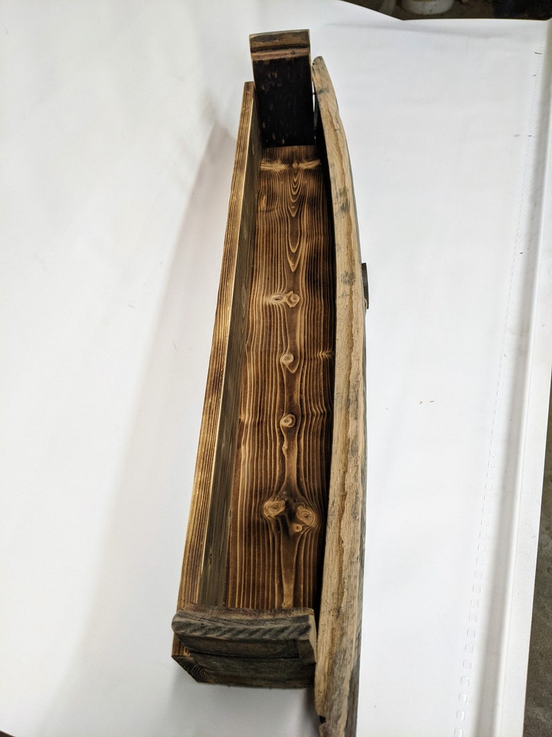 K&ouml;nnte beinhalten: Ein Holzregal aus wiederverwendeten Weinfassdauben. Das Regal ist gebogen und hat eine nat&uuml;rliche Holzoptik. Es ist perfekt f&uuml;r die Pr&auml;sentation von kleinen Gegenst&auml;nden oder Pflanzen.