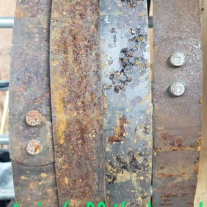 Pode incluir: Close-up de aros de barril de metal enferrujado e desgastado. Os aros s&atilde;o presos por parafusos. O texto "As is / off the barrel" &eacute; vis&iacute;vel em verde. Os aros mostram sinais de idade e exposi&ccedil;&atilde;o.