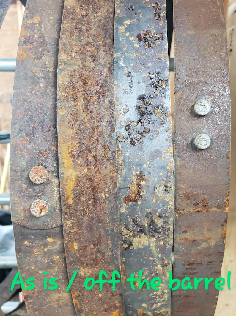 Pode incluir: Close-up de aros de barril de metal enferrujado e desgastado. Os aros s&atilde;o presos por parafusos. O texto "As is / off the barrel" &eacute; vis&iacute;vel em verde. Os aros mostram sinais de idade e exposi&ccedil;&atilde;o.
