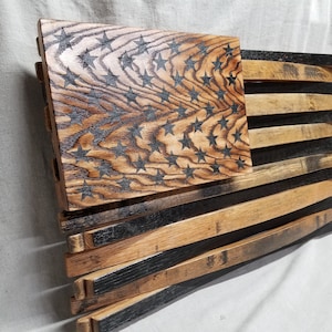 K&ouml;nnte beinhalten: Eine amerikanische Holzflagge aus wiederverwendeten Bourbon-Fassdauben. Die Sterne sind in das Holz gebrannt und die Streifen sind aus den Fassdauben gefertigt.