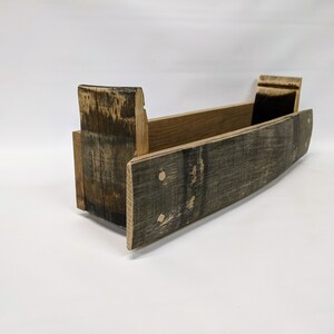 May include: A wooden shelf made from reclaimed whiskey barrel staves. The shelf is curved and has a natural wood finish.
