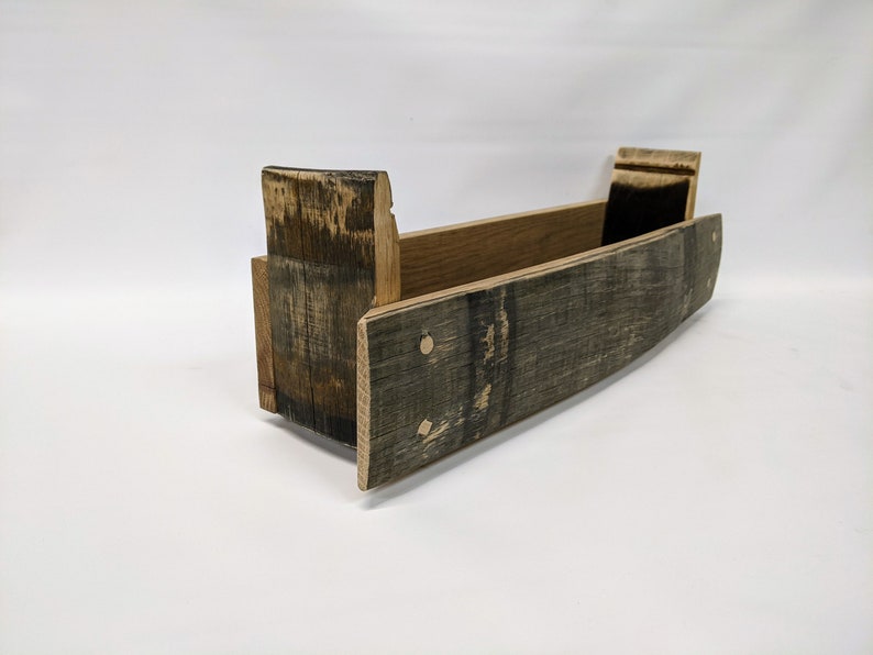 May include: A wooden shelf made from reclaimed whiskey barrel staves. The shelf is curved and has a natural wood finish.