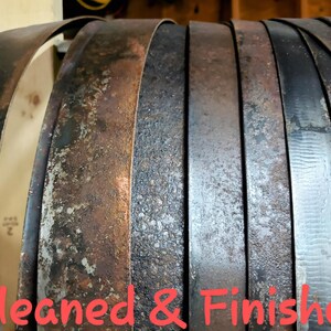 Pode incluir: Close-up de v&aacute;rias bandas de barril de metal em v&aacute;rios est&aacute;gios de limpeza e acabamento. As bandas exibem uma gama de cores, do marrom escuro ao prata, com texturas vis&iacute;veis. O texto "Cleaned & Finished" est&aacute; em vermelho.